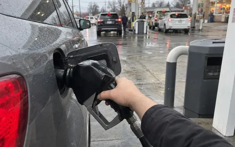 Hand filling a car’s gas tank at a pump before a delivery shift