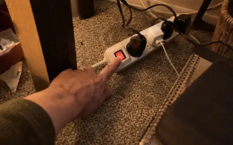 Hand switching off a power strip to save electricity