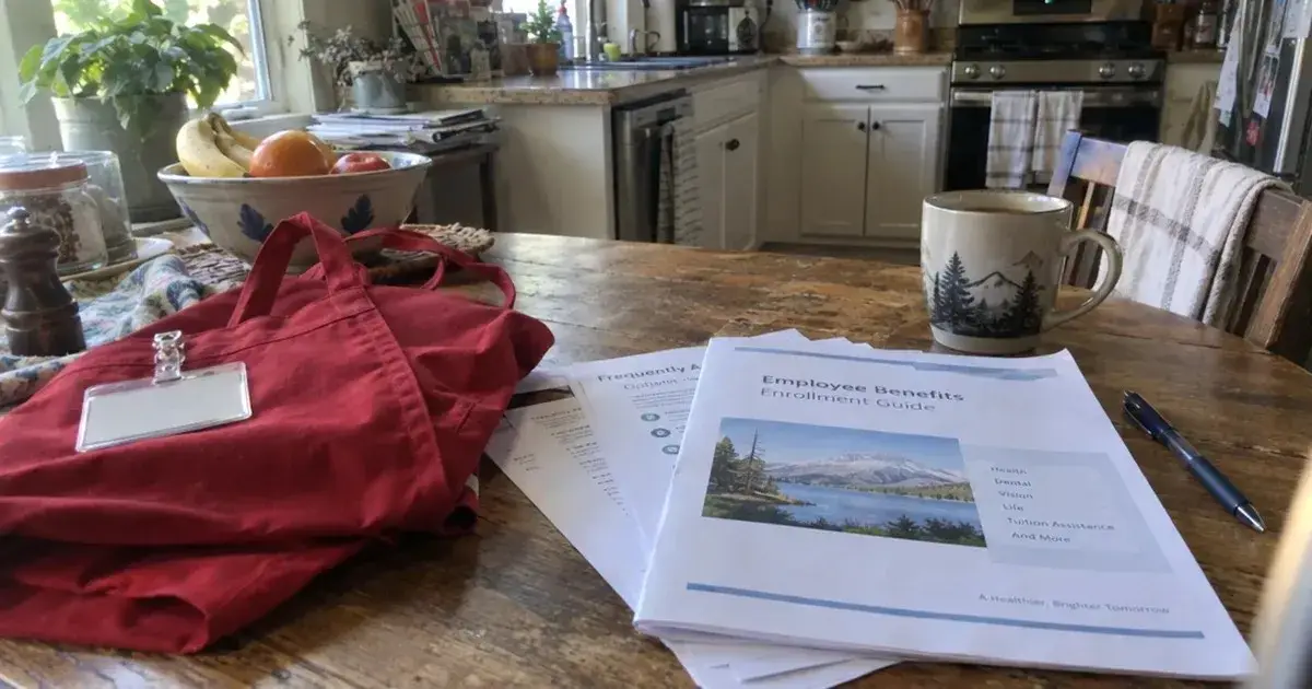 Store work apron and a printed employee benefits packet on a kitchen table