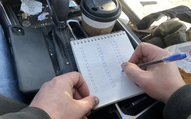 Hands tracking Spark offer pay and gas costs in a notebook inside a car